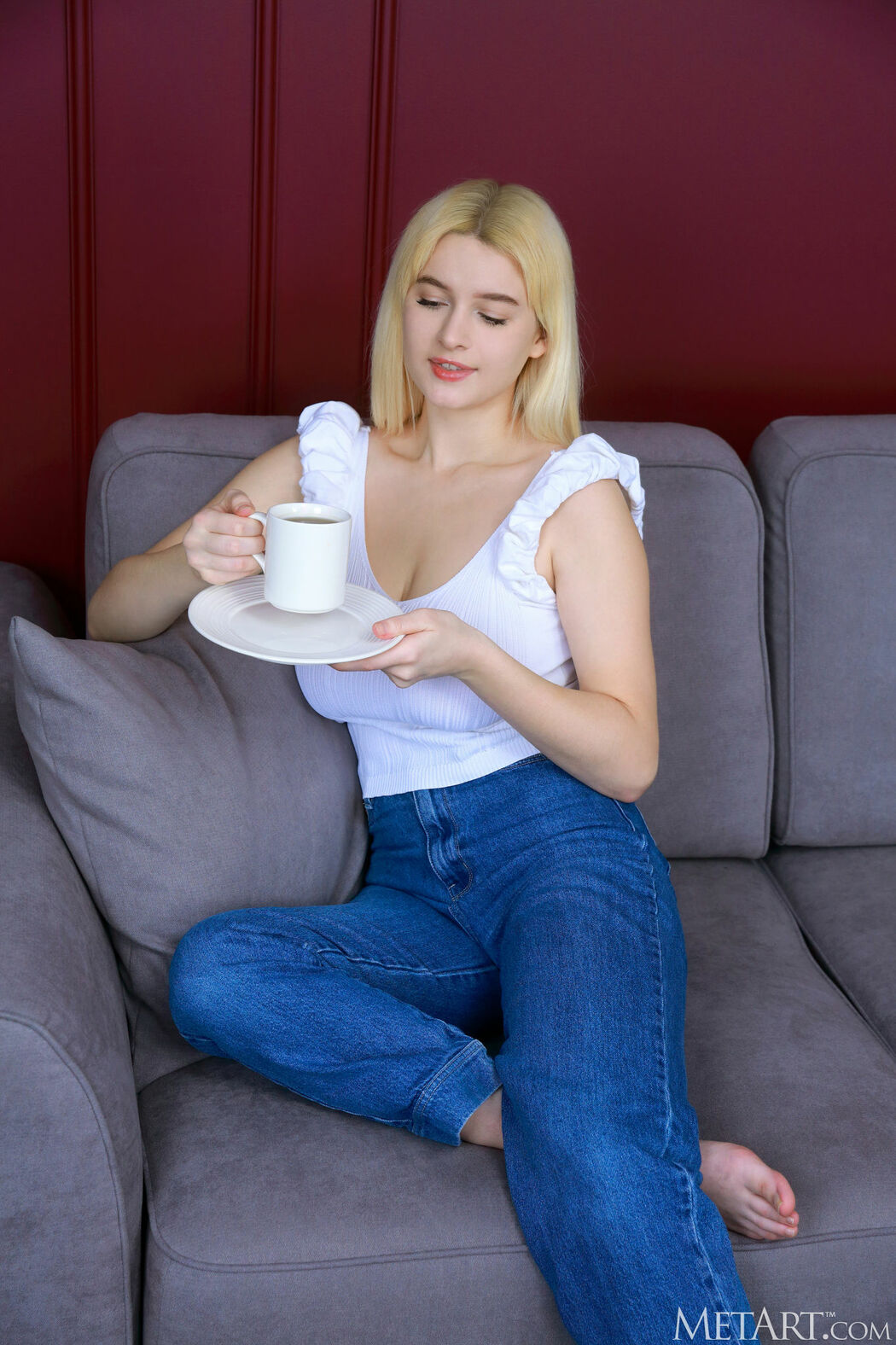Miss Mia Sips Tea On Sofa In Cozy T-shirt And Jeans Cover Photo